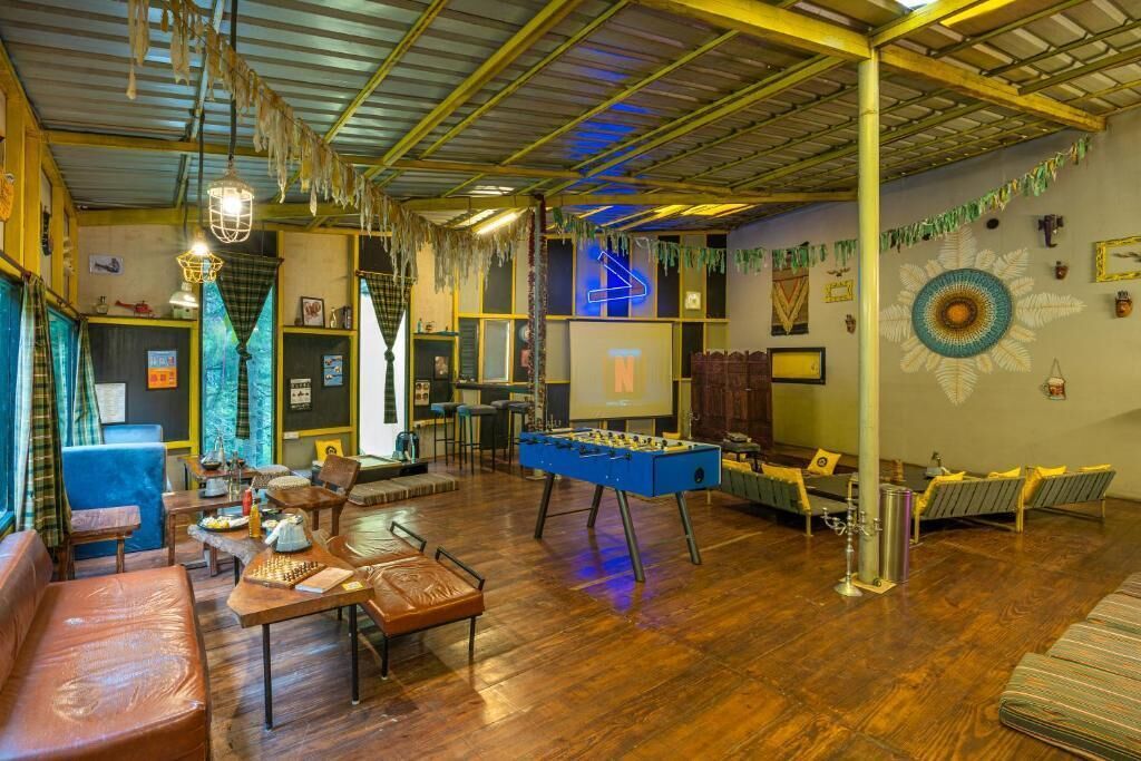 A spacious room with a foosball table, a sofa, a coffee table, and a small bar area.