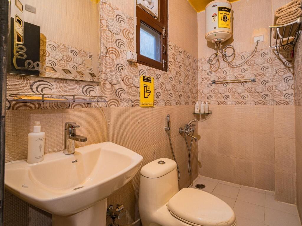 A bathroom with a sink, toilet, and shower. There is a towel rack and a sign on the wall.
