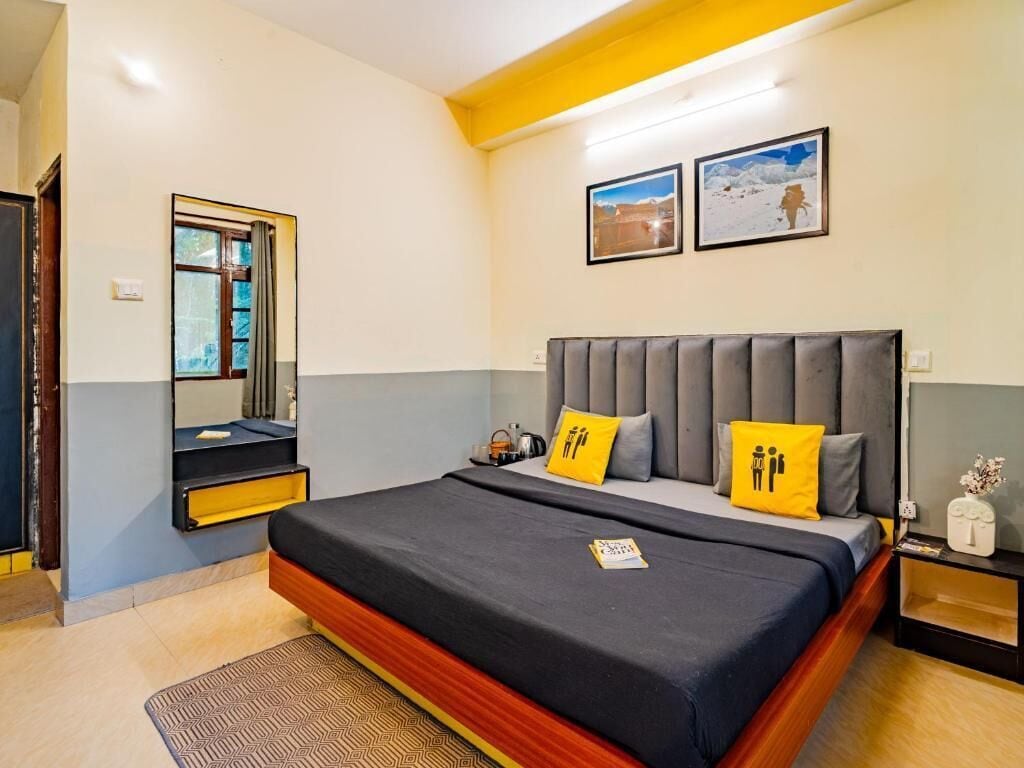 A bedroom with a bed, a nightstand, a mirror, and two framed pictures on the wall.