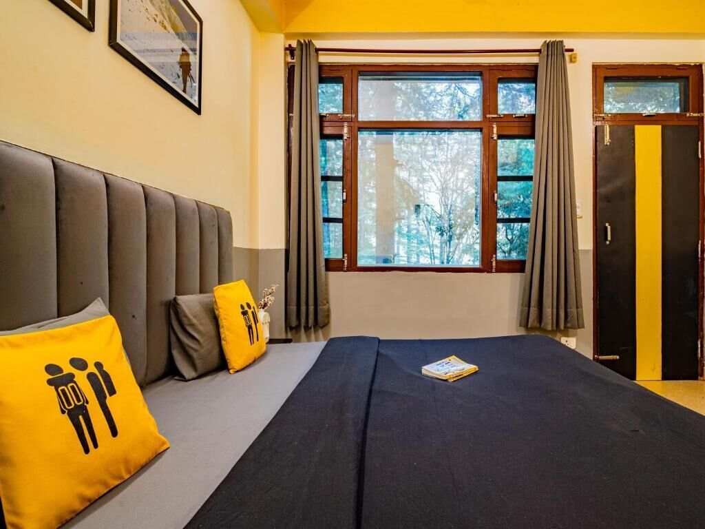 Een slaapkamer met een bed, kussens, een raam met gordijnen en een deur.