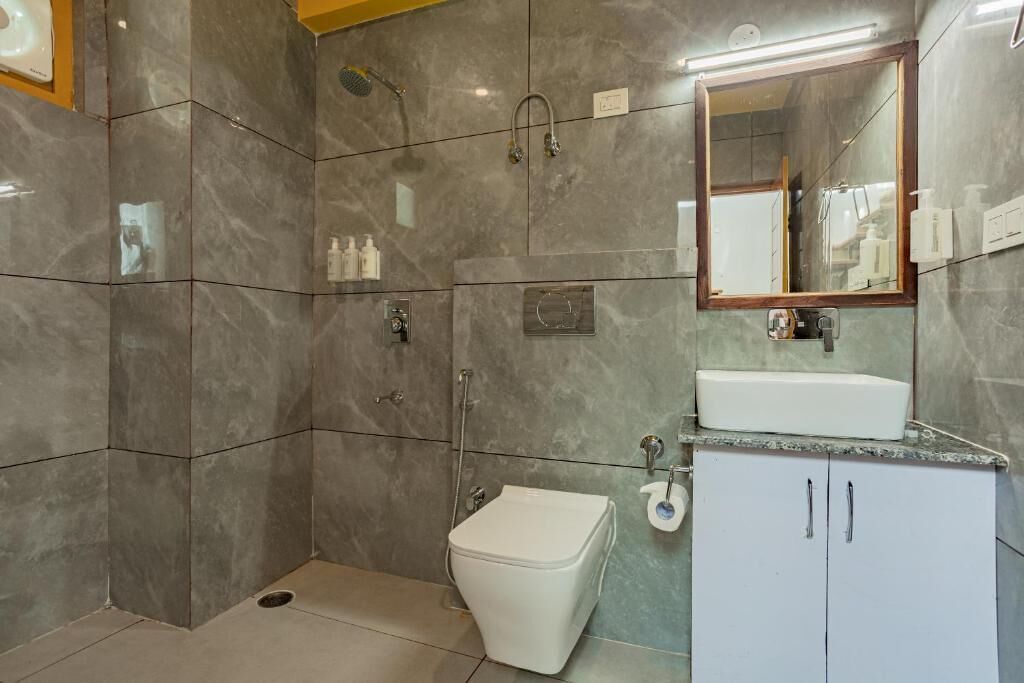 A modern bathroom with a shower, toilet, sink, and a mirror.
