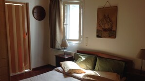 Ein Schlafzimmer mit einem Bett, einem Nachttisch, einem Fenster mit Vorhängen, einer Wanduhr und einer Wanddekoration.