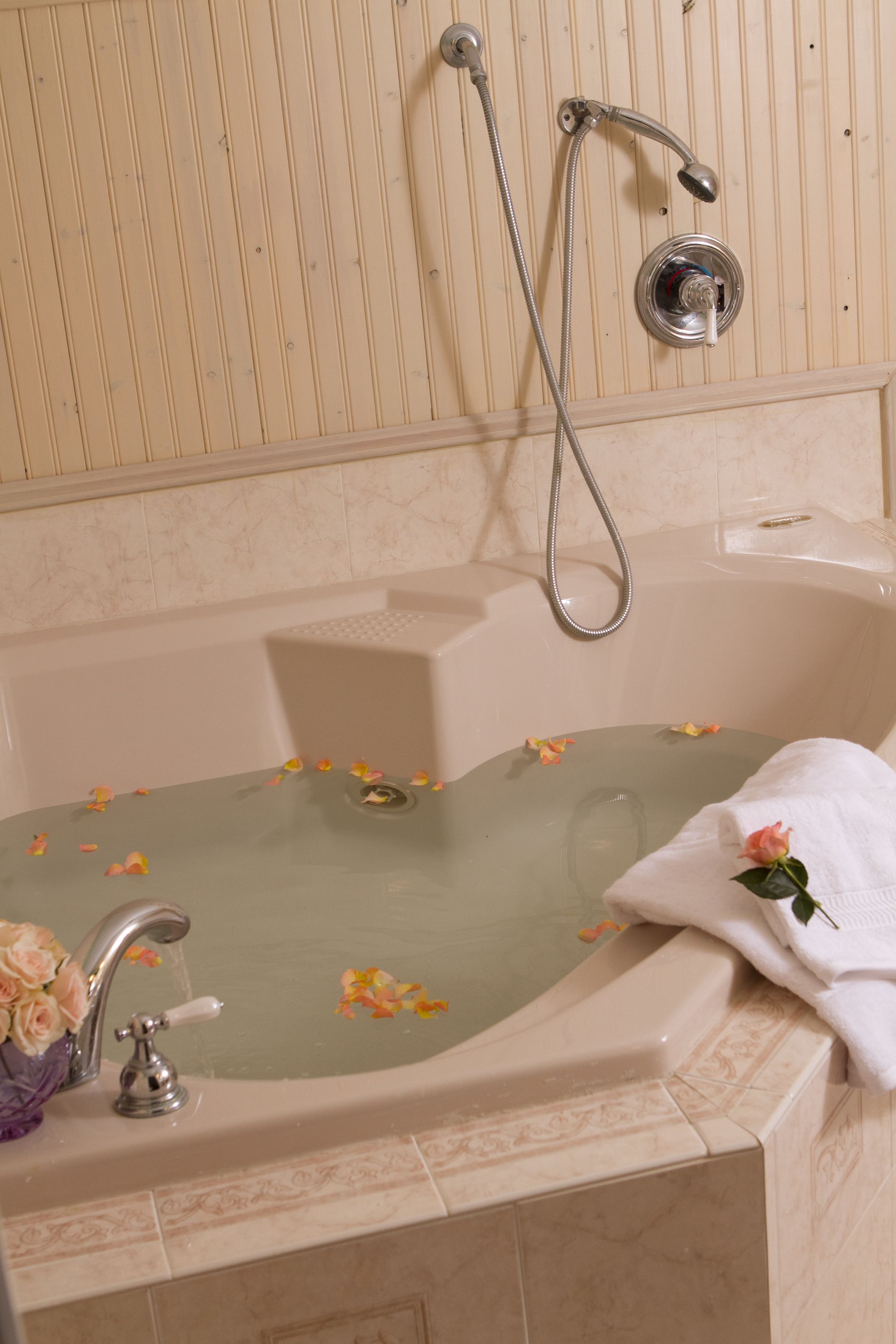 Una bañera con un cabezal de ducha, un grifo y una toalla.