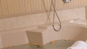 Una bañera con un cabezal de ducha, un grifo y una toalla.