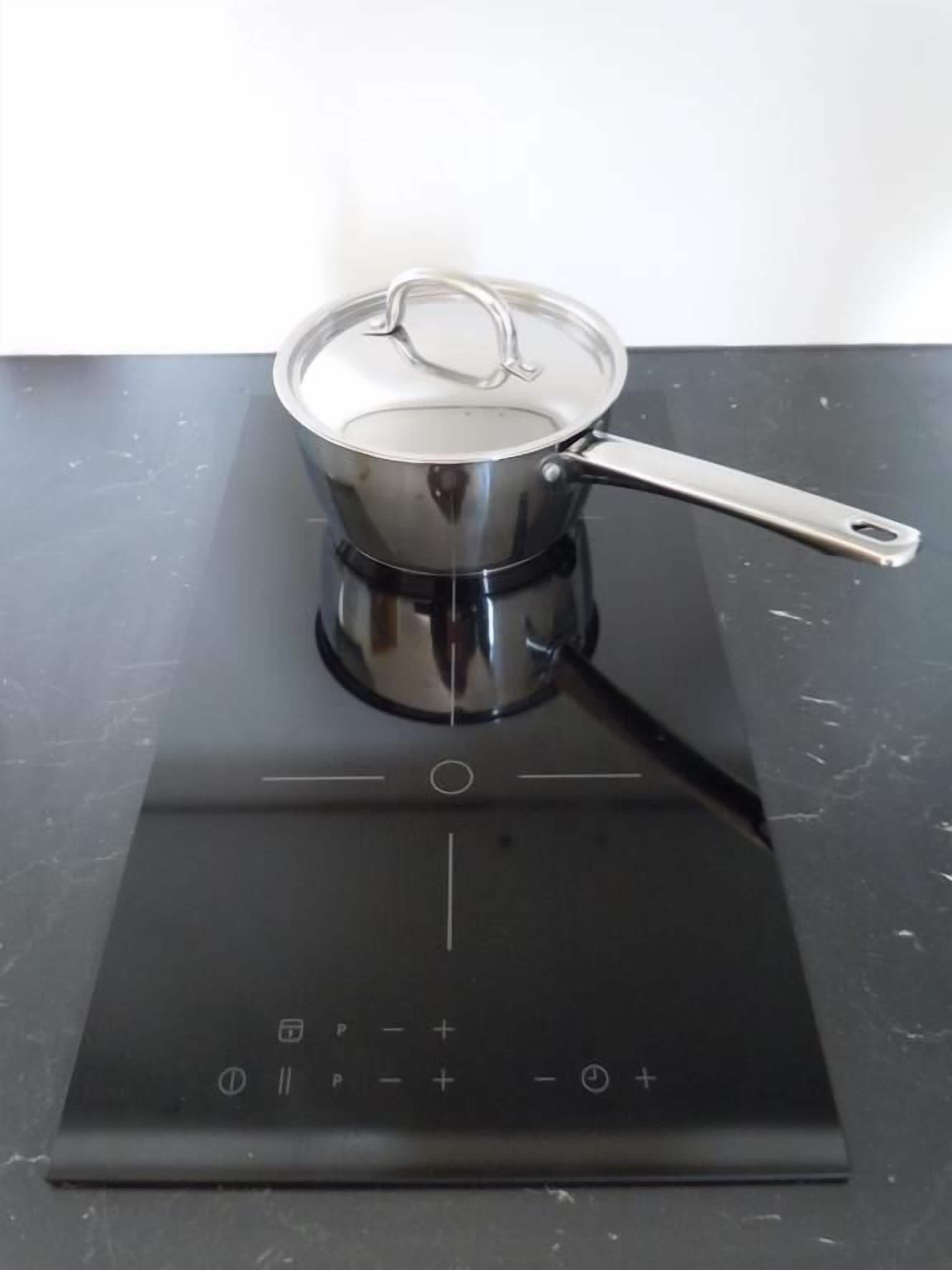 A black induction cooktop with a pot on it.