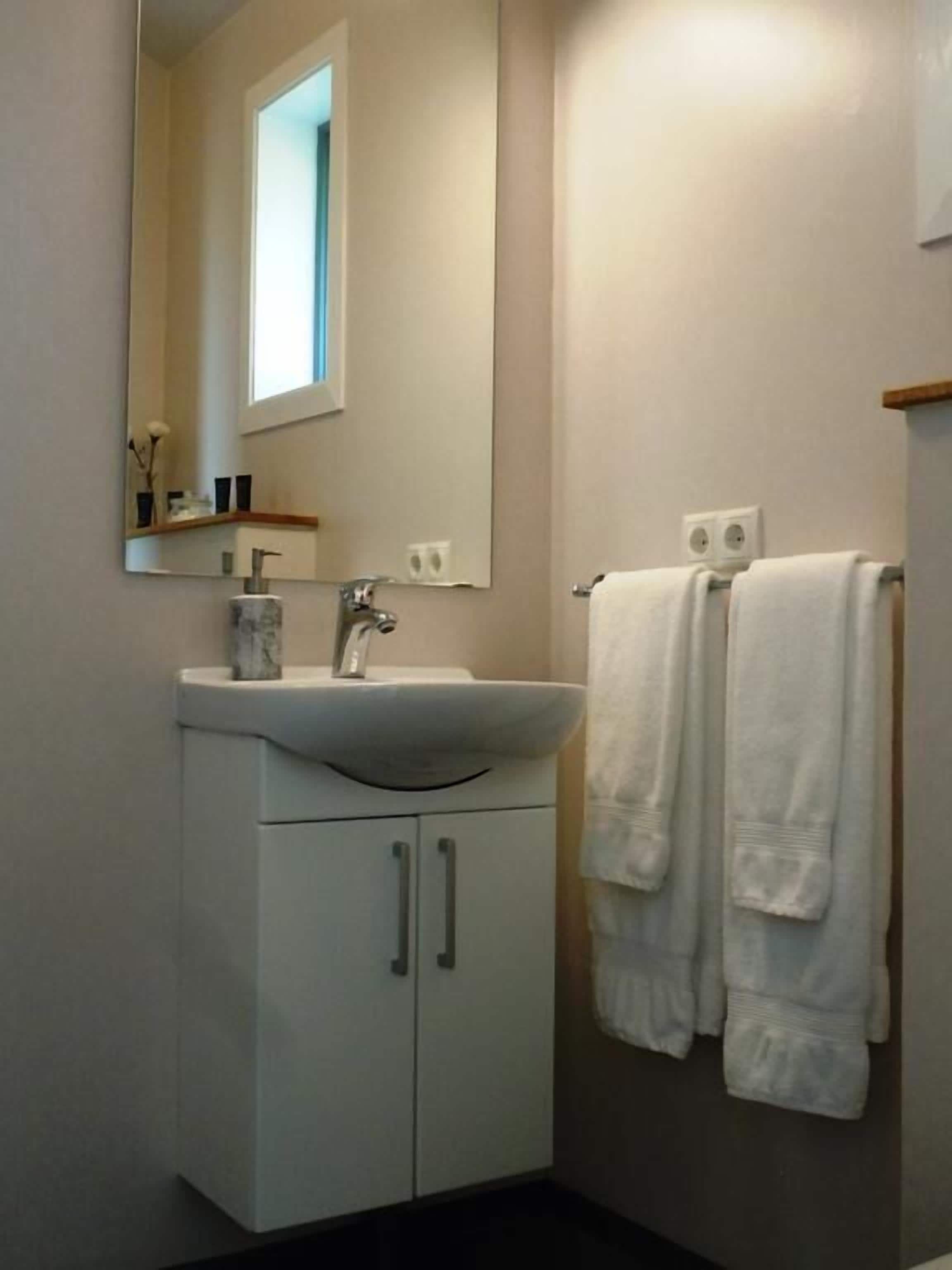 A bathroom with a white sink, mirror, and two towels hanging on a rack.