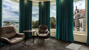 A room with two leather chairs, a small round table, and large windows with teal curtains. - Motel One Warsaw-Chopin (Warsaw)