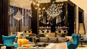 A modern lounge area with comfortable seating, a bar in the background, and decorative lighting. - Motel One Warsaw-Chopin (Warsaw)