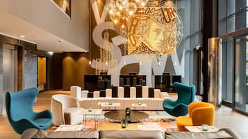 Een moderne lobby met een zithoek, een grote decoratieve wand en uitzicht op de stad.