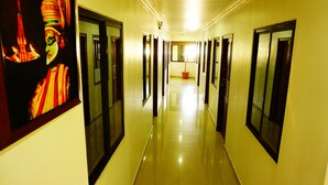 A long, narrow hotel corridor with doors on both sides, leading to individual rooms. - Thayamkery's Royal inn (Kanayannur)