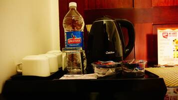 Un plateau de petit-déjeuner dans une chambre d’hôtel, avec une bouteille d’eau, une machine à café et une tasse de café.