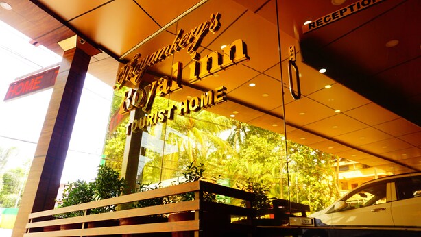 A hotel entrance with a reception desk, a push button for the reception, and a sign indicating the hotel's name. - Thayamkery's Royal inn (Kanayannur)
