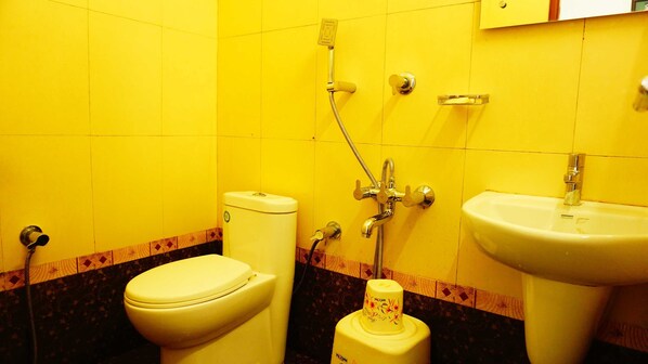 A bathroom with yellow walls, a white toilet, a sink, and a shower.