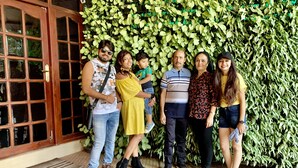 A group of people standing in front of a wall with green foliage. - Thayamkery's Royal inn (Kanayannur)