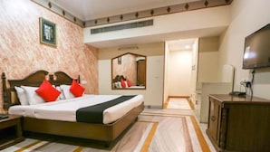 Una habitación de hotel con una cama, un espejo, un televisor y un armario de madera.