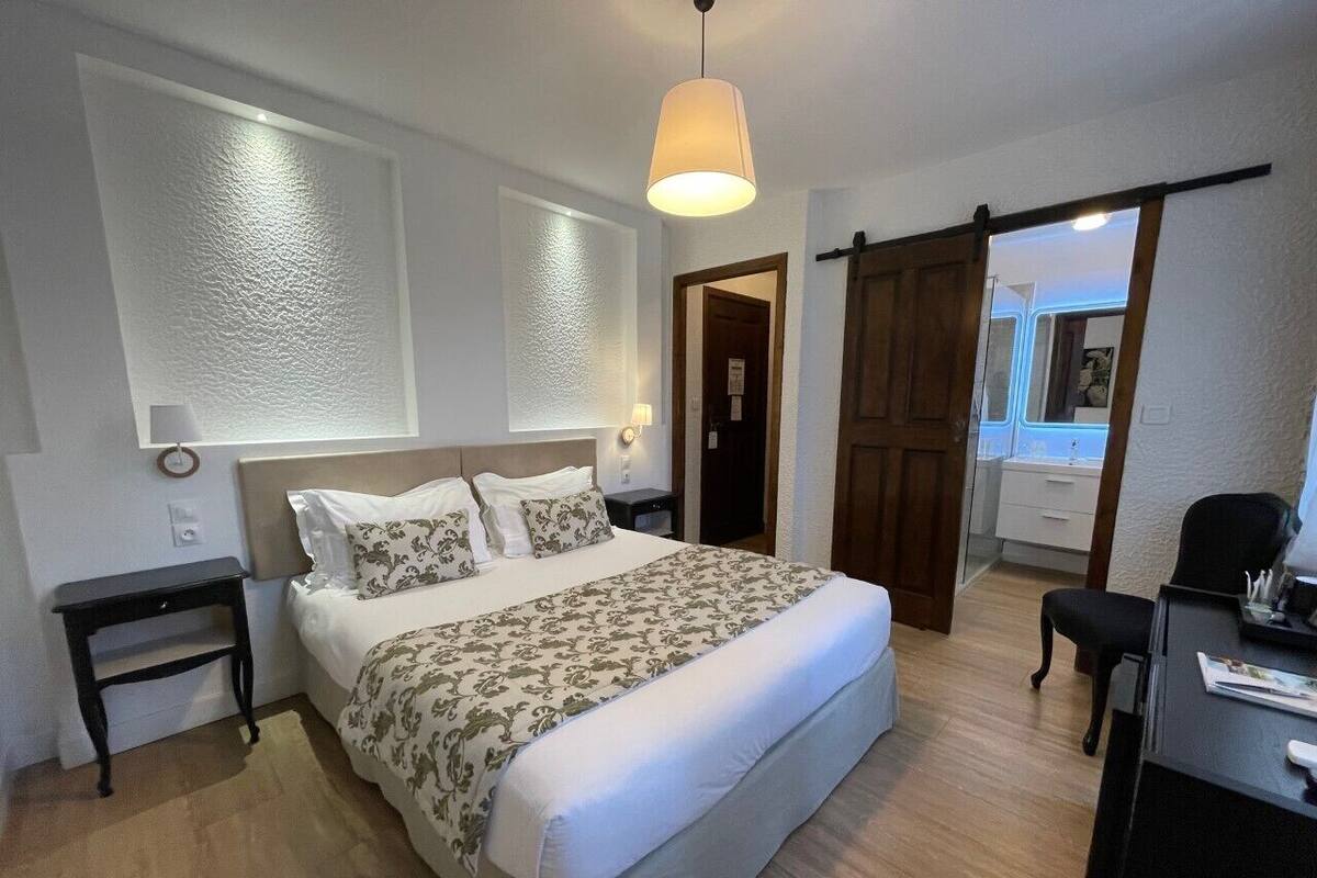 A bedroom with a bed, bedside tables, a desk, and a chair.