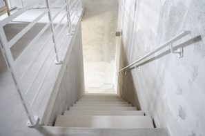 Een trap met witte leuningen en een betonnen muur.