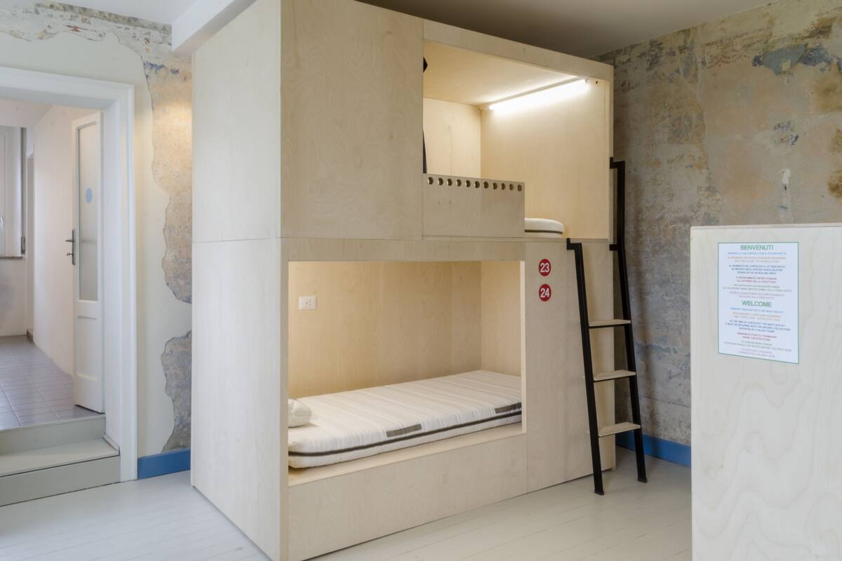 A bunk bed room with a ladder, a welcome sign, and a door leading to another room.