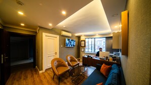 A modern living room with a sofa, two armchairs, a glass coffee table, and a desk with a laptop. - All Seasons Suites (Istanbul)
