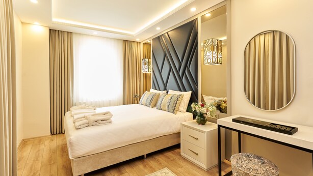 A modern bedroom with a bed, bedside table, and a mirror. - All Seasons Suites (Istanbul)