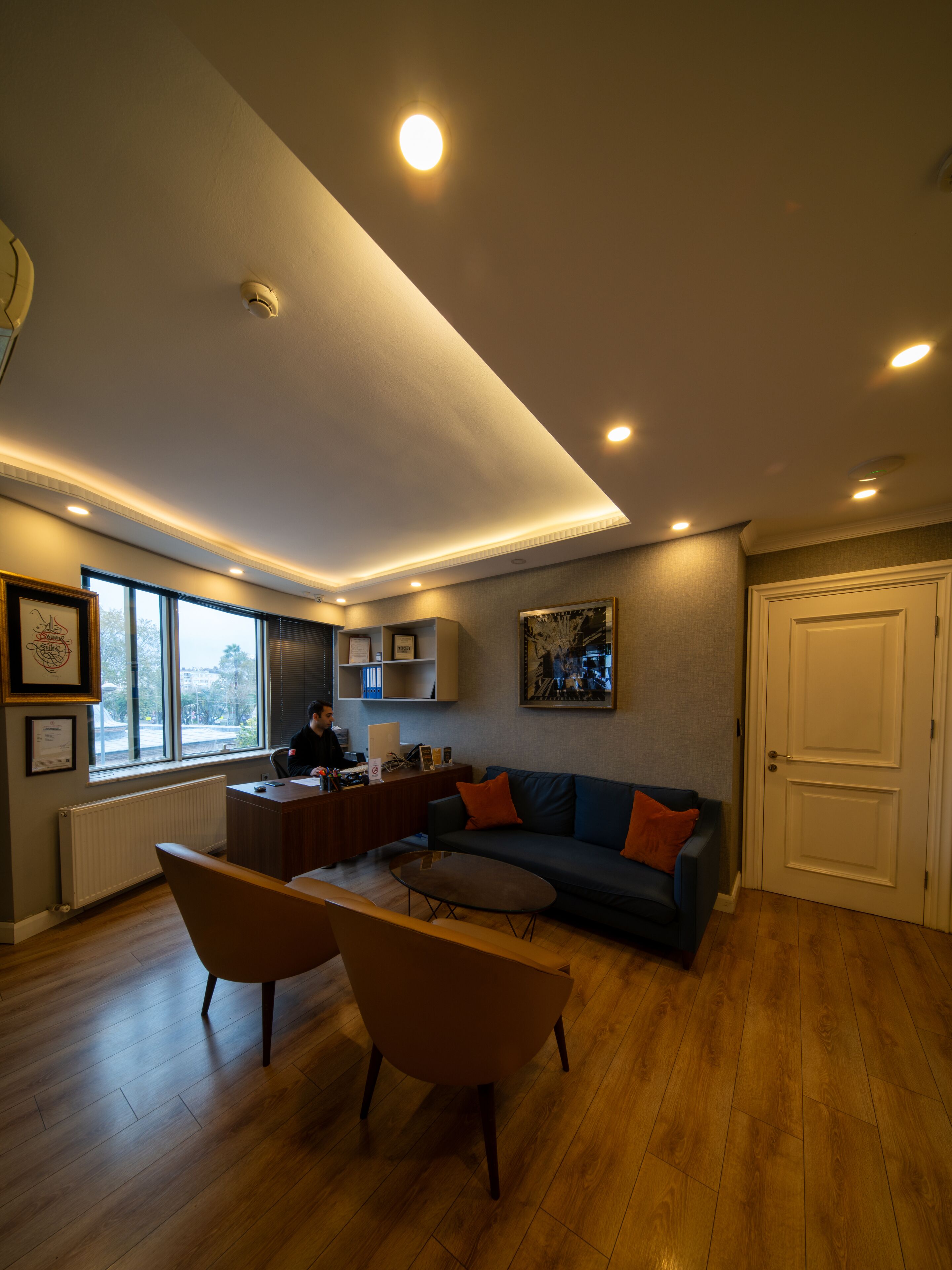 Un salon moderne avec un plancher en bois, un canapé, une table basse et un bureau avec un ordinateur.