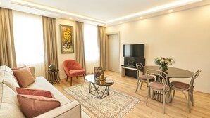 A modern living room with a sofa, a red armchair, a round coffee table, and a dining area with a table and chairs. - All Seasons Suites (Istanbul)