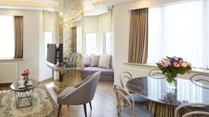 A modern living room with a sofa, a dining table, and a TV. - All Seasons Suites (Istanbul)
