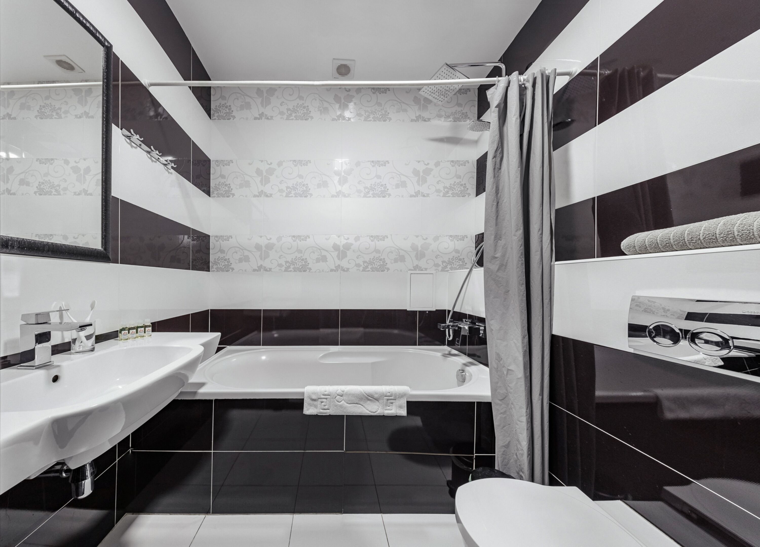 A modern bathroom with a bathtub, two sinks, a shower, and a large mirror.