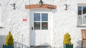 A white building with a white door, two potted plants, a brick arch, and a sign indicating a 4-star rating. - East Trewent Farm B&B (Pembroke)