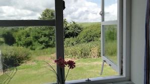 A window with a view of a grassy field and trees, a white window frame, and a clear sky. - East Trewent Farm B&B (Pembroke)