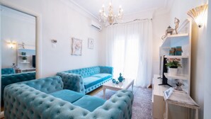 A living room with a blue sofa, a coffee table, and a decorative shelf. - Acropolis Deluxe Apt Must (Thessaloniki)