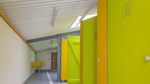 A hallway with lockers, a yellow table, and a door with a green sign.
