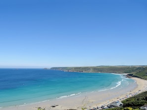 Ein Küstenstrand mit blauem Himmel, sandigem Ufer und Blick aufs Meer.