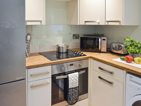 A modern kitchen with a built-in oven, microwave, toaster, and a sink.