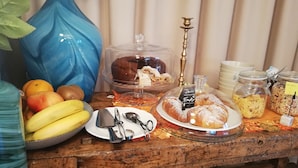 Uma mesa de buffet com diversos alimentos, incluindo frutas, doces e cereais.