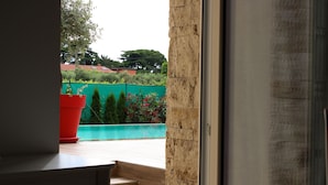 Vista de dentro de um quarto com piso de madeira e uma planta em vaso vermelho.