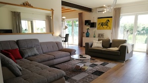 Uma sala de estar moderna com um sofá seccional, um sofá menor, uma mesa de centro e um tapete.