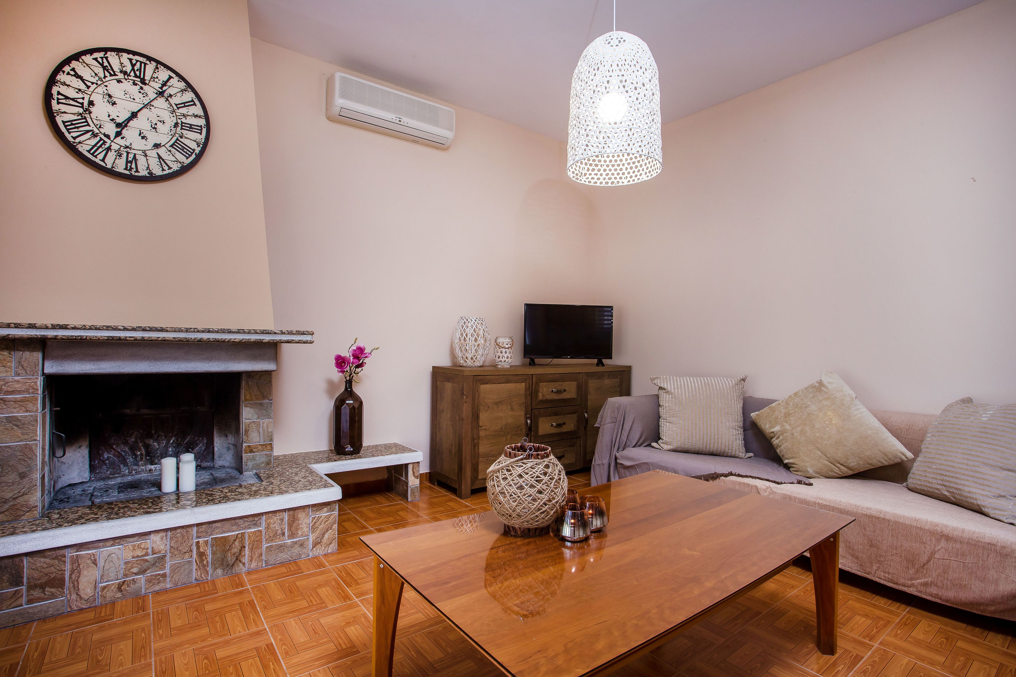 Una sala de estar con chimenea de piedra, una mesa de centro de madera, un sofá y un televisor.