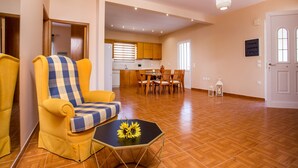 Uma sala de estar moderna com uma poltrona amarela, um sofá quadriculado e uma área de jantar com móveis de madeira.