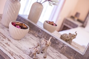 Une table en bois agrémentée d’objets décoratifs, notamment un vase, un bol contenant des fleurs séchées et une petite figurine d’éléphant.