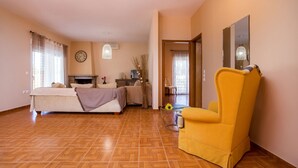 Quarto amplo com cama, poltrona amarela, escrivaninha e espelho.
