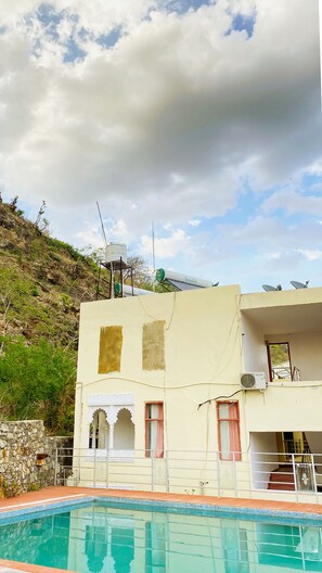 Un bâtiment doté d’une piscine, d’antennes paraboliques et de réservoirs d’eau, situé sur le versant d’une colline.