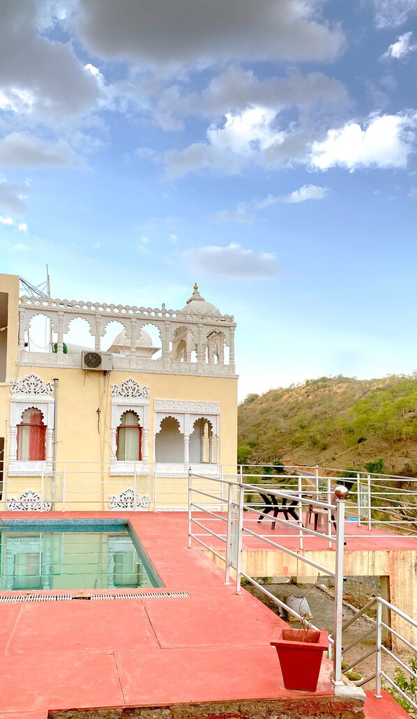 Um edifício com arcos brancos elaborados e uma área de piscina com cobertura vermelha.