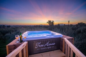 A hot tub with a wooden deck and a sign that reads "Tree House luxury spa."