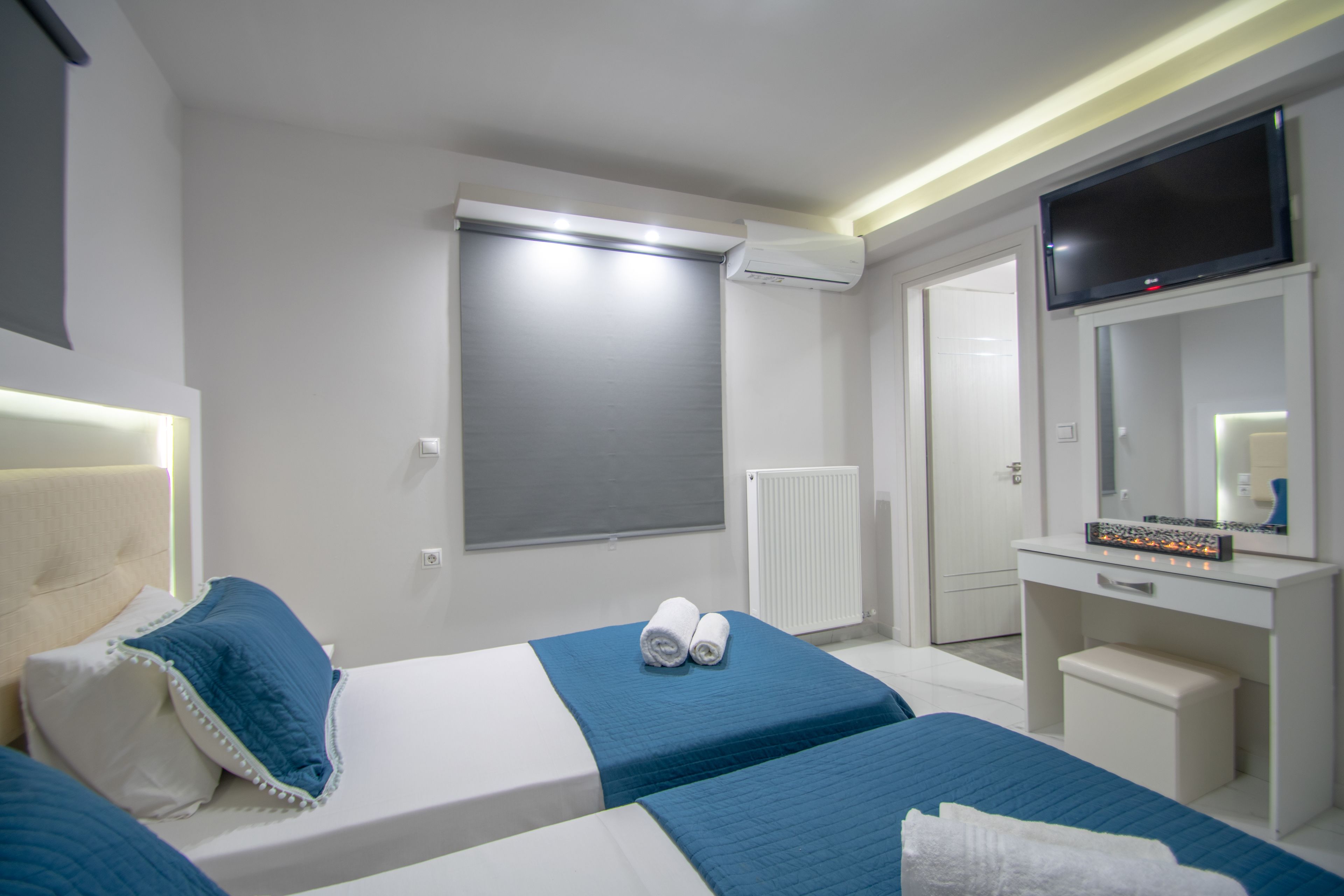 A hotel room with two beds, a TV, a desk, and a mirror.