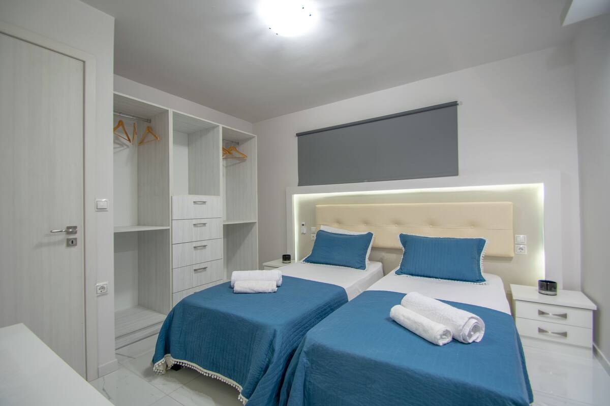 Une chambre d’hôtel avec deux lits, une armoire et une table de chevet avec une lampe.