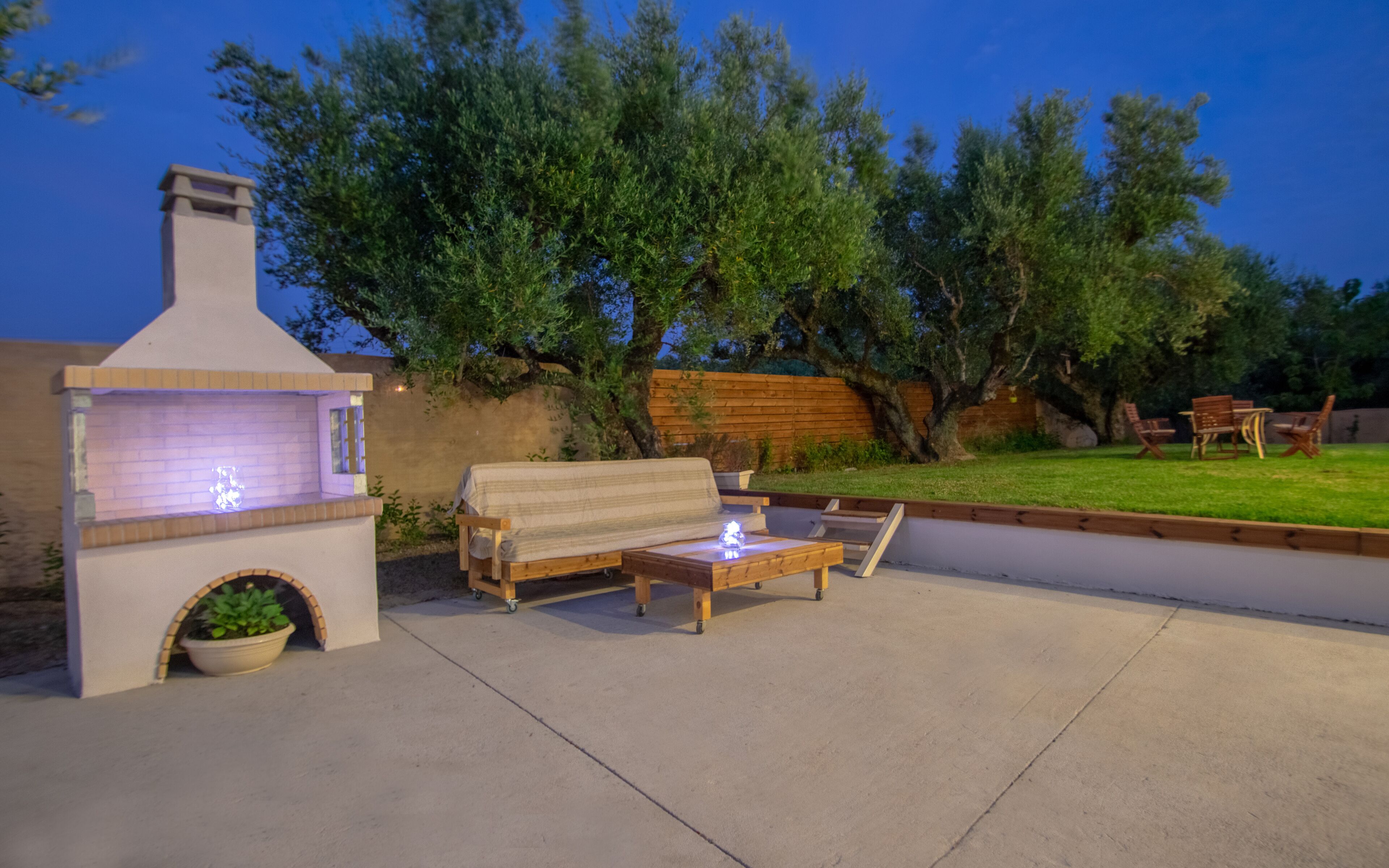An outdoor patio with a built-in grill, a wooden bench, and a table.