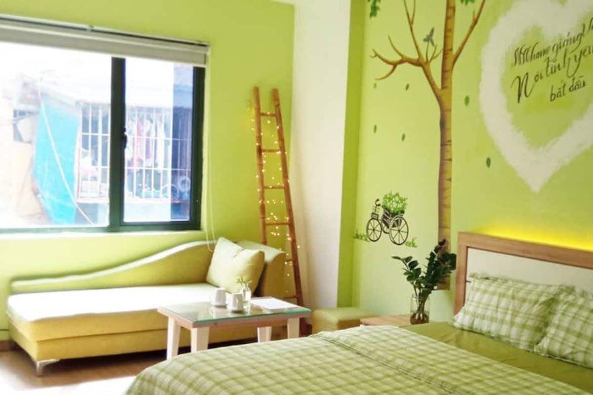 A bedroom with a bed, a window, a ladder, and a wall decal.