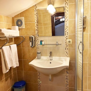 A bathroom with a sink, mirror, towel rack, and a shower area.