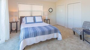 A bedroom with a bed, two nightstands, a chair, and a ceiling fan. - Sunsets on the Sand (Indian Shores)